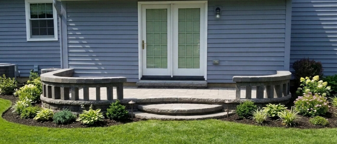 Curved raised stone planter wall built beside patio doors with plantings