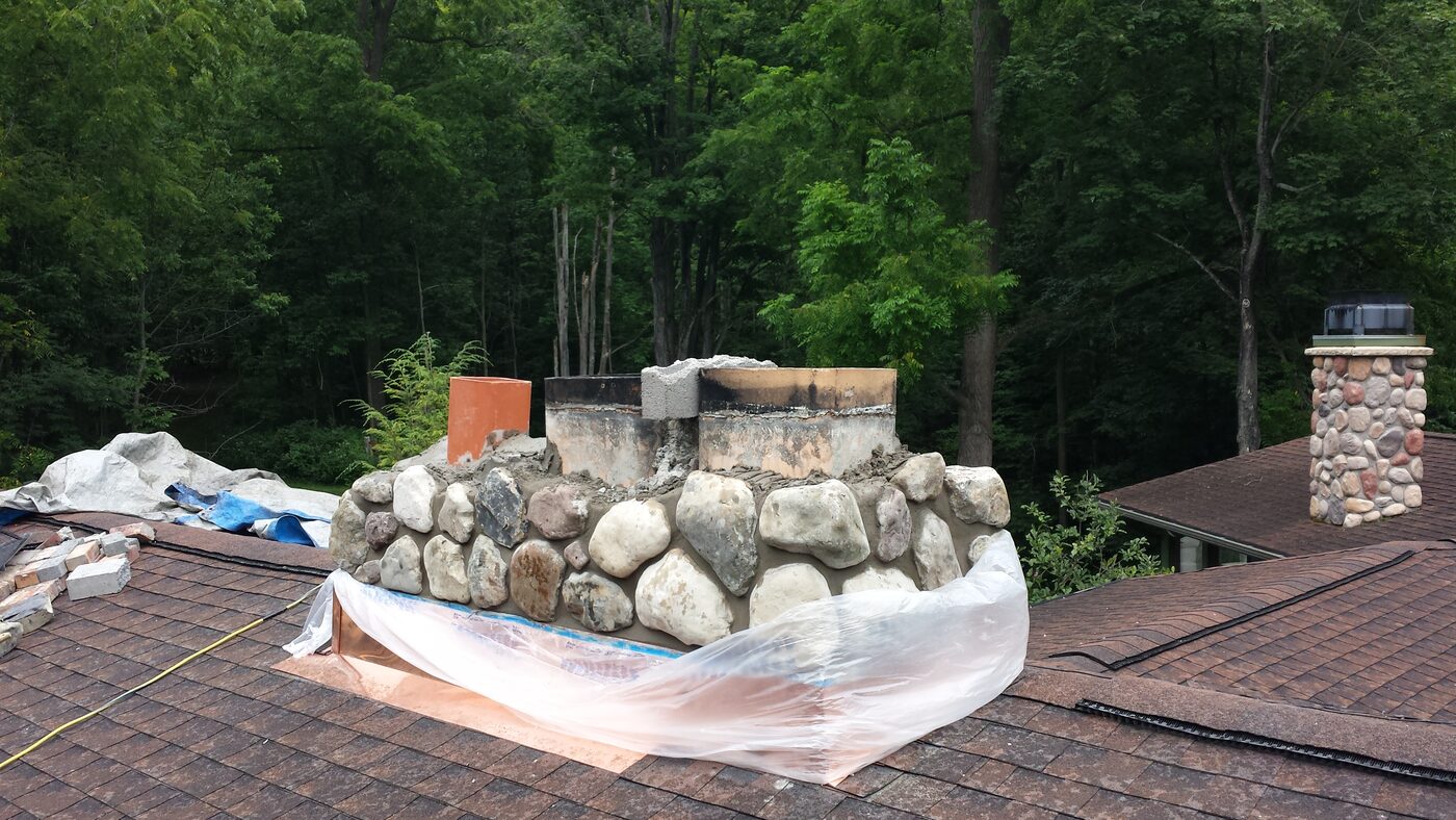 Fieldstone chimney under construction on a rooftop