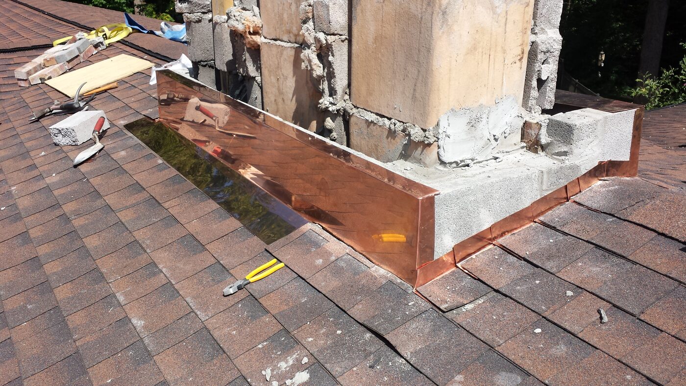 New copper chimney flashing and cricket installed on a shingle roof